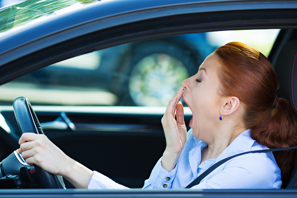 Únava - žena za volantem auta zívá