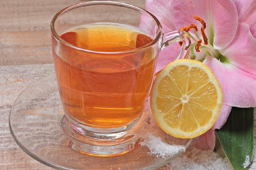 čaj ve sklenici, půlka citronu a fialový květ