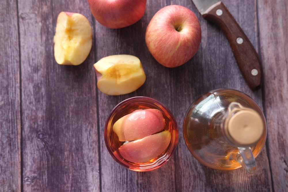 Jablečný ocet a jablka na stole