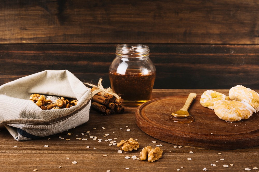 Pohankový med ve sklenici, ořechy v plátěném pytlíku, skořice a lžička
