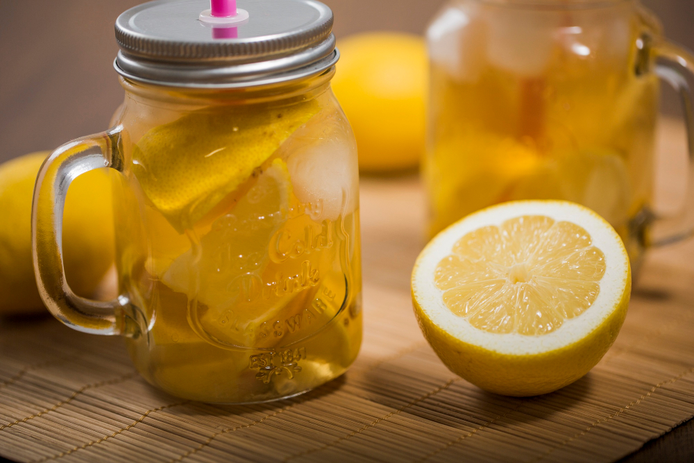 Nakrájený citron ve skleněném hrnku s víčkem a polovina citronu vpravo na stole