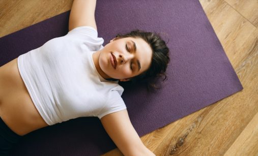 žena leží na fialové podložce, relaxuje