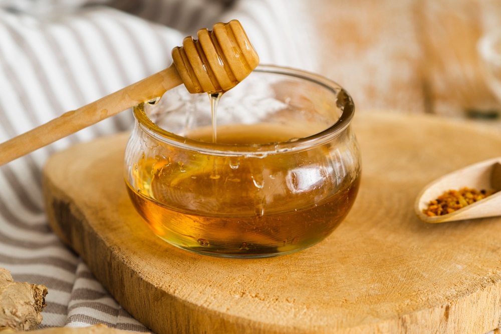 Skleněná miska s medem s dřevěným nabíratkem na med