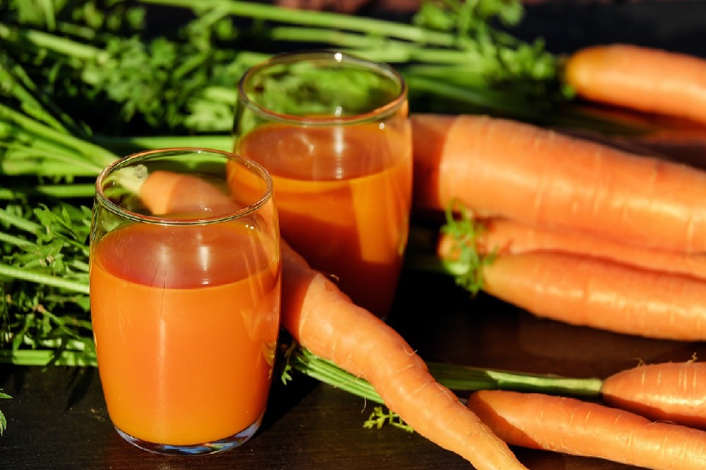 Mrkev a dvě sklenice mrkvové šťávy jako doplnění vitamínu A