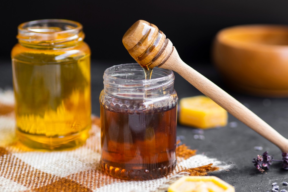 Sklenice medu s opřenou naběračkou na med