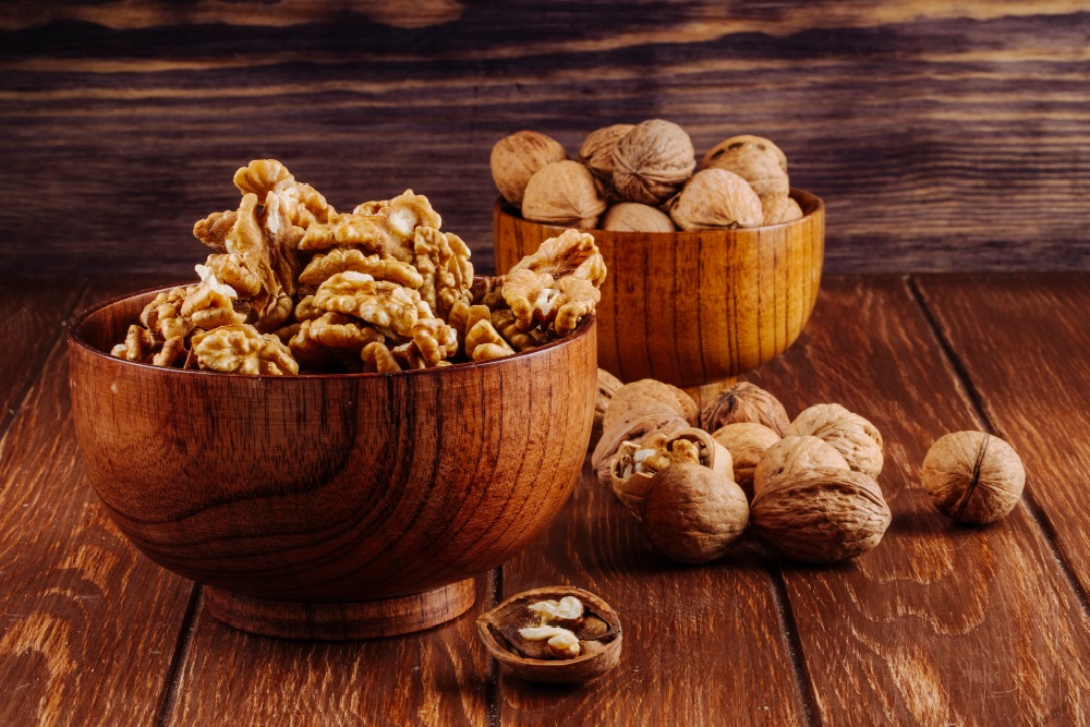 Vlašské ořechy v dřevěných miskách a na dřevěném stole