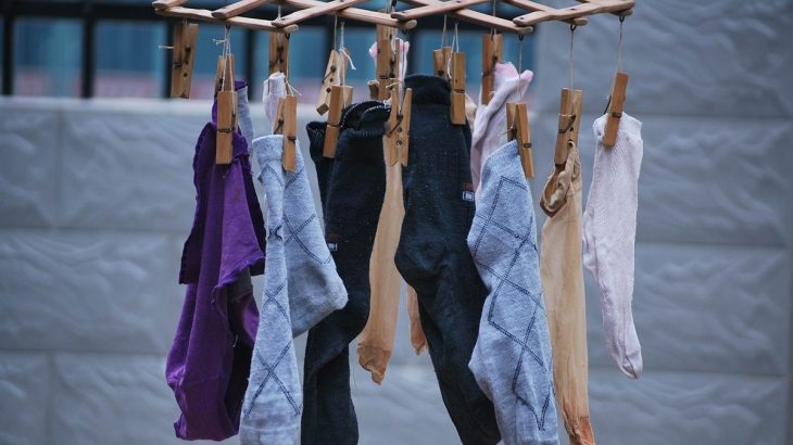 Různé ponožky pověšené na sušáku na prádlo
