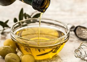 Miska olivového oleje s olivami okolo