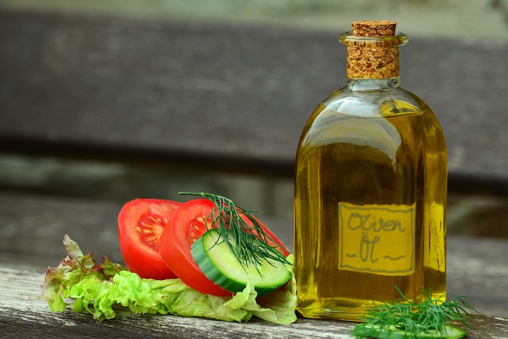 Olivový olej v lahvi obložený nakrájenou zeleninou