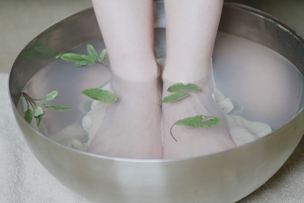 Nohy ve škopku s vodou a bylinkami