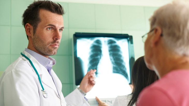 Lékař ukazující na obrazovku s rentgenem plic pacientovi