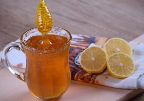 Med ve sklenici s rozpůlenými citrony na utěrce