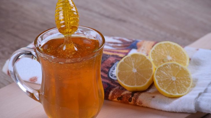 Med ve sklenici s rozpůlenými citrony na utěrce