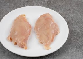 Dva syrové kuřecí řízky na bílém talíři na tmavě šedém pozadí