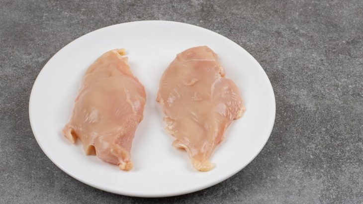 Dva syrové kuřecí řízky na bílém talíři na tmavě šedém pozadí