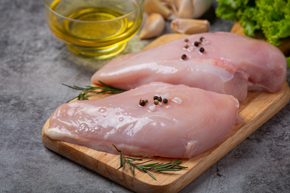 Syrové kuřecí prsní řízky na prkénku s kořením a olejem