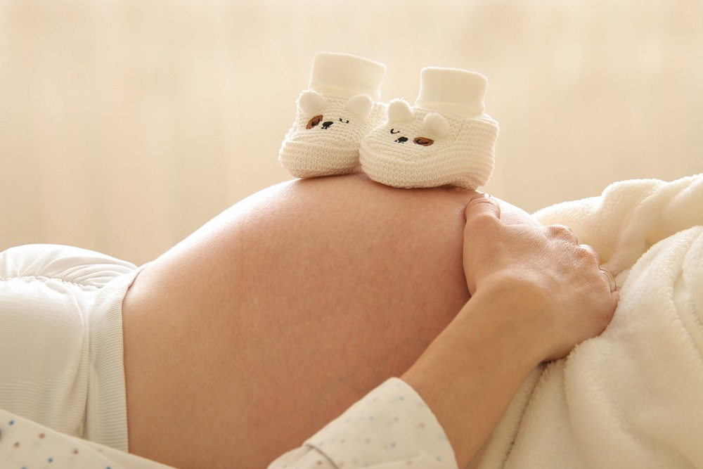 Břicho těhotné ženy s botičkami pro miminko