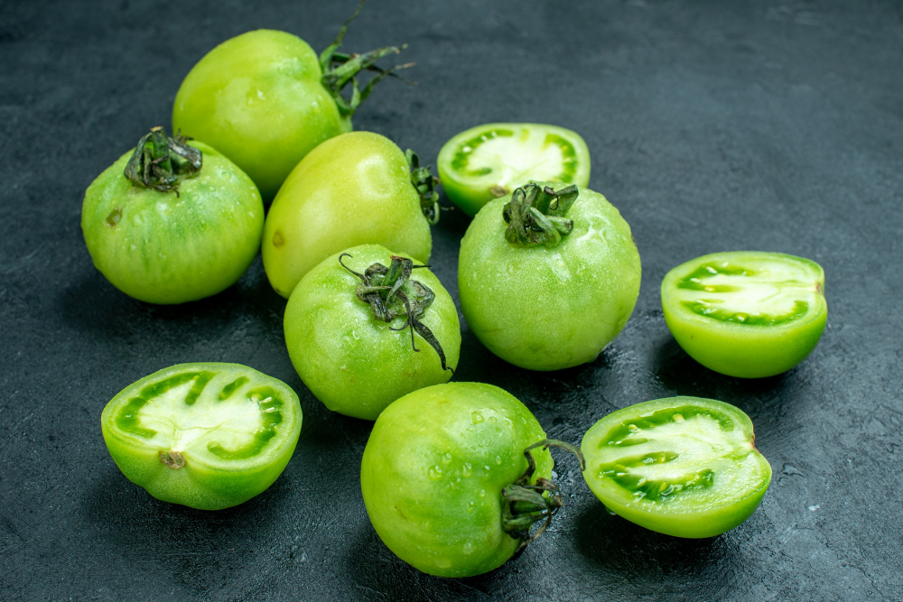 Zelená rajčata na tmavém podkladě, některá celá, některá přepůlená