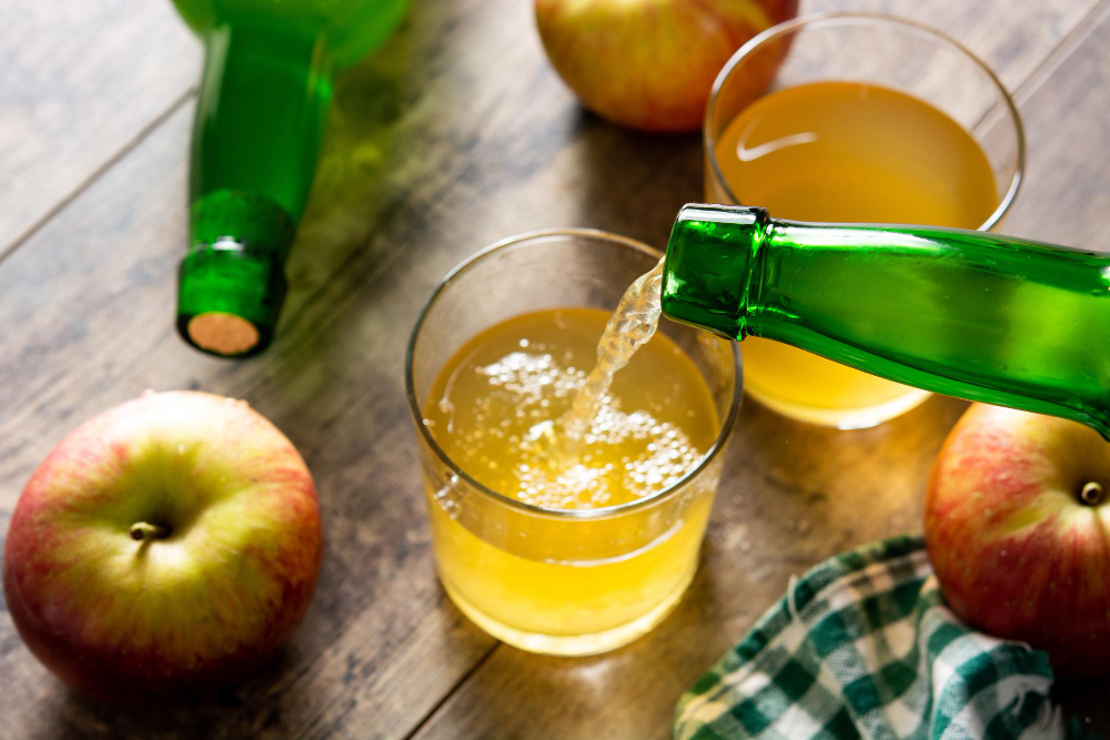 Jablečný ocet ve sklenicích na dřevěném stole