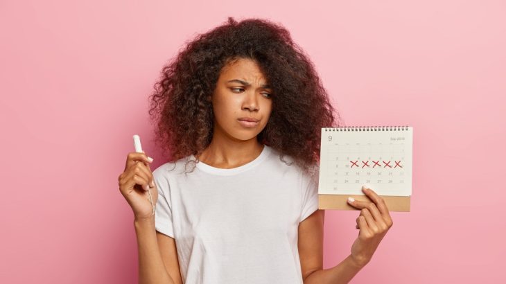 Žena s tampónem a kalendářem se zaškrtanými dny menstruace