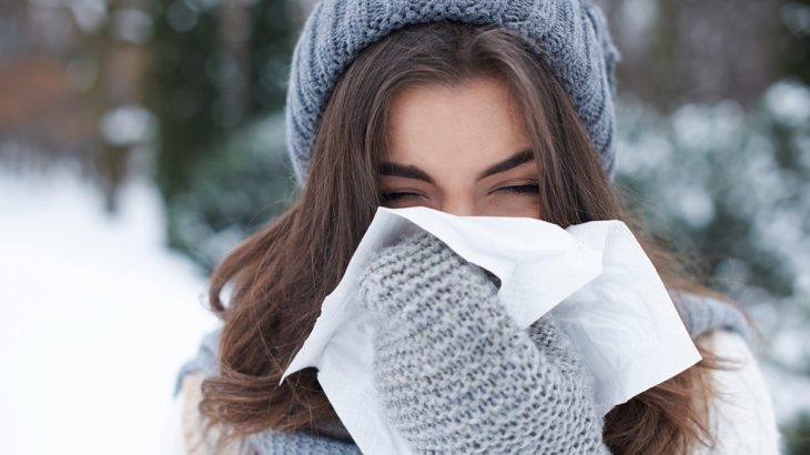 Žena v zimě s kapesníkem před ústy a nosem