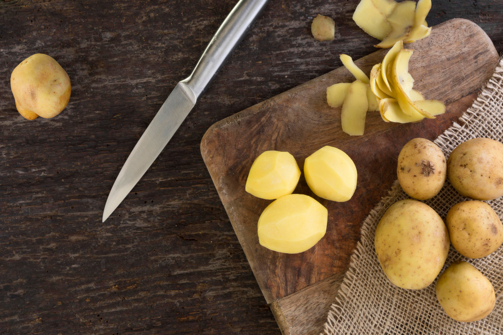 Nakrájené a oloupané brambory s bramborami ve slupce jako aranžmá na stole