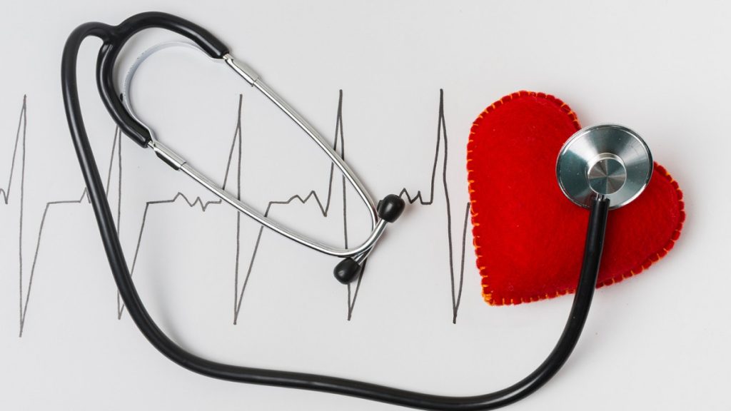 Látkové srdce a stetoskop na pozadí s nakresleným pulzem