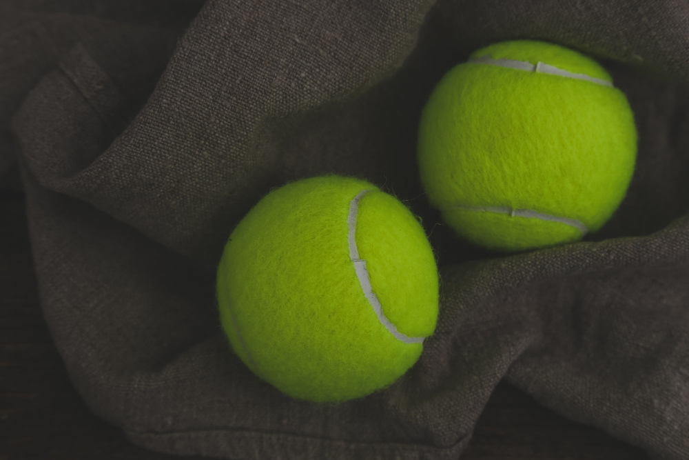 Dva tenisové míčky na tmavé látce