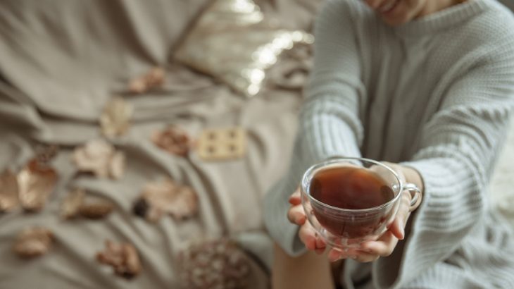 Žena ve svetru s hrnkem bylinkového čaje