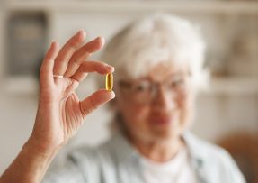 Starší žena držící kapsli vitamínu D