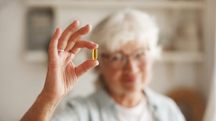 Starší žena držící kapsli vitamínu D
