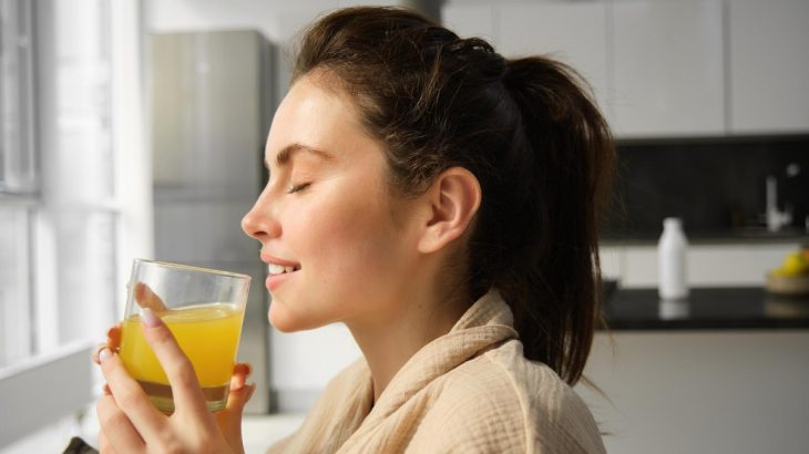 Mladá žena pijící limonádu poránu v kuchyni