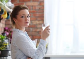 Zdravá žena v kuchyni se sklenicí nápoje