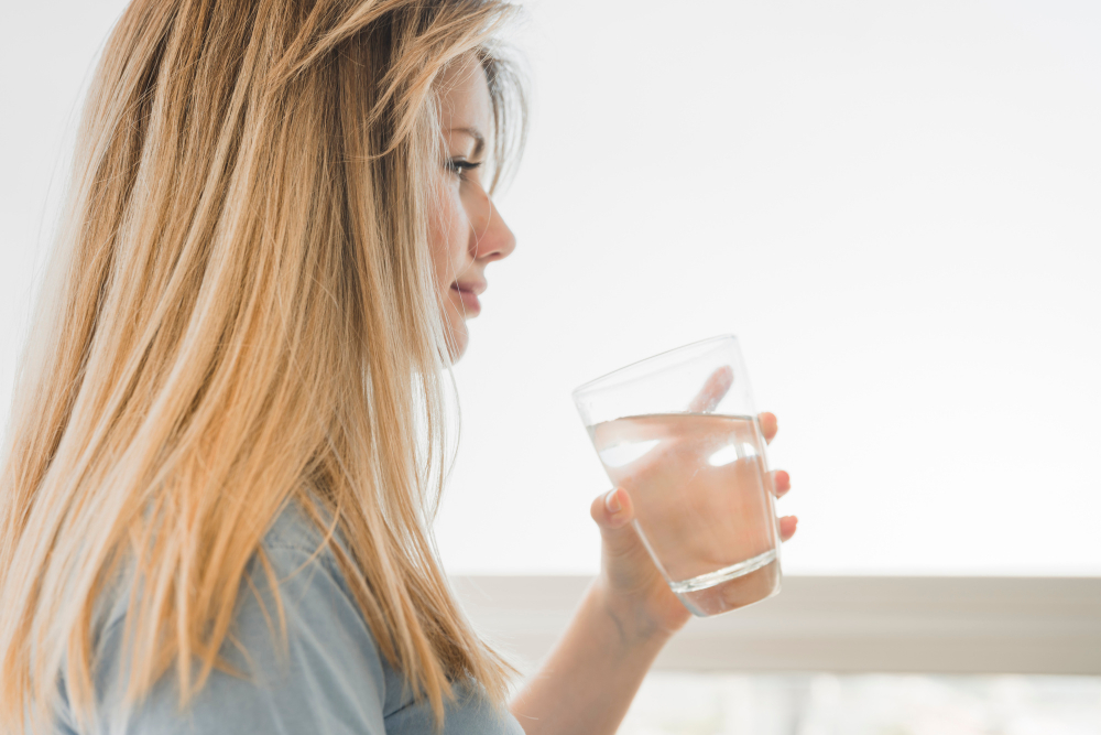 Blonďatá žena držící sklenici s vodou