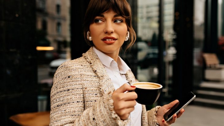 Žena s kávou a mobilem v ruce
