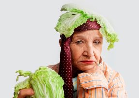 Starší žena s listem čínského zelí na hlavě