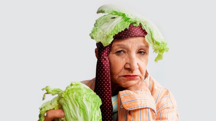 Starší žena s listem čínského zelí na hlavě