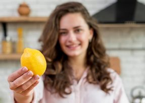 Mladá žena v kuchyni držící citron