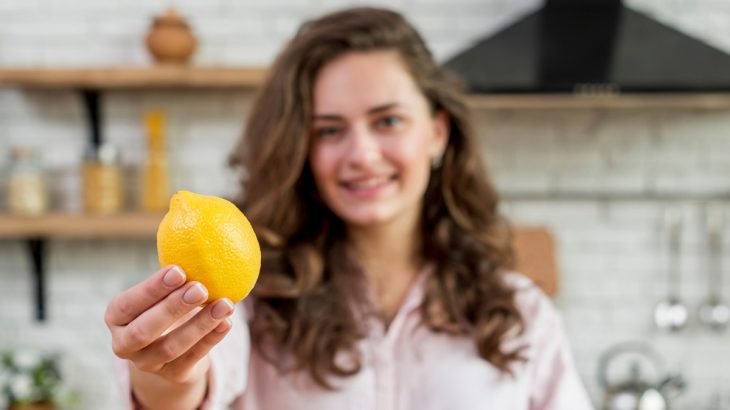 Mladá žena v kuchyni držící citron