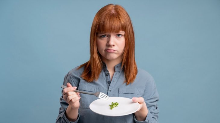 Žena ohrnující nos nad talířem s brokolicí