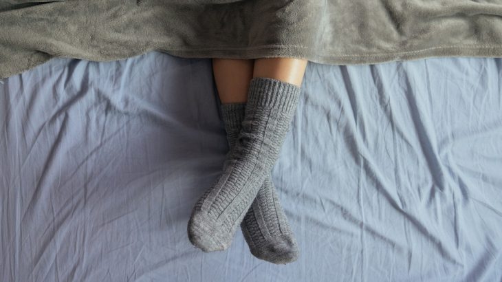 Nohy v šedivých ponožkách koukající zpod deky